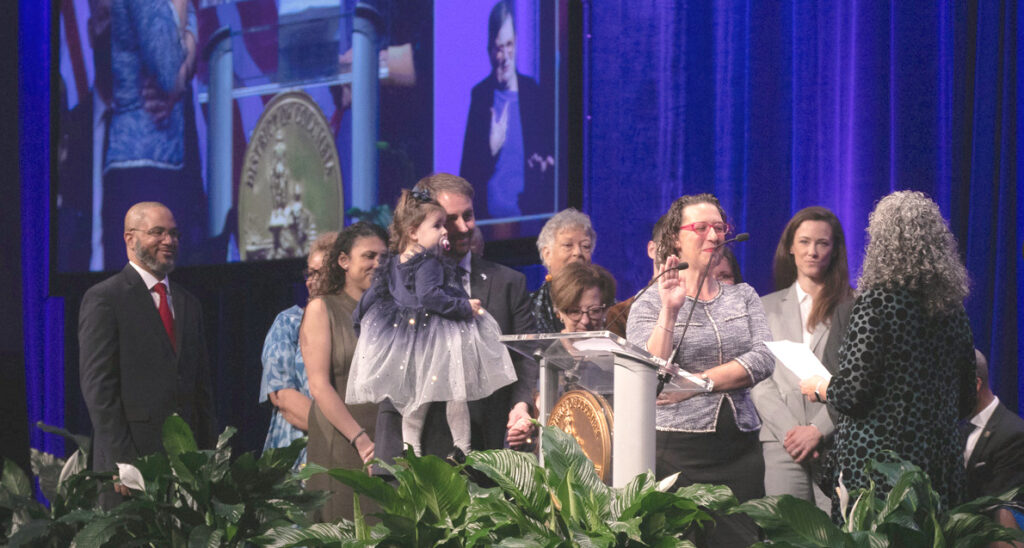 Brianne K Nadeau raises her right hand as she is sworn in to her new term in office surrounded by her family and Council staff