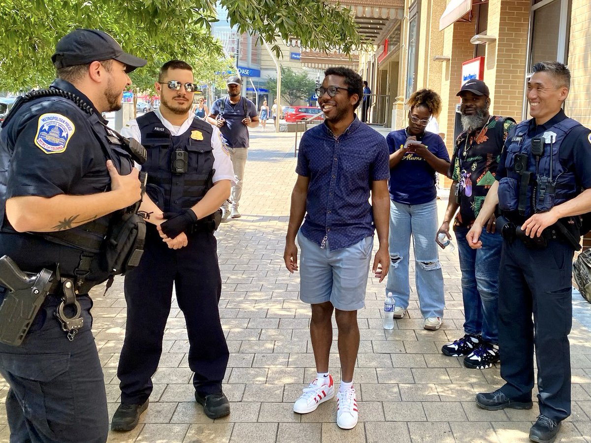 residents and police officers chatting and laughing on a sidewalk