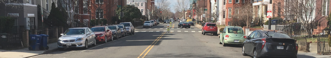 View looking down S Street with cars parked on both sides and rowhouses.