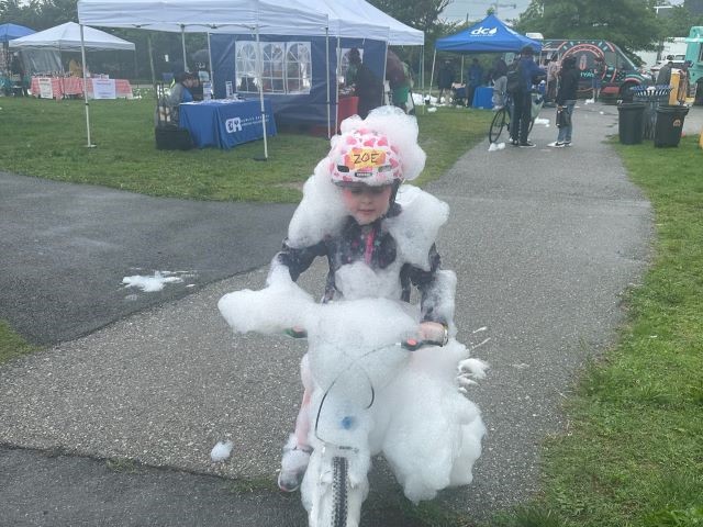 Girl rides bike and is covered in bubbles