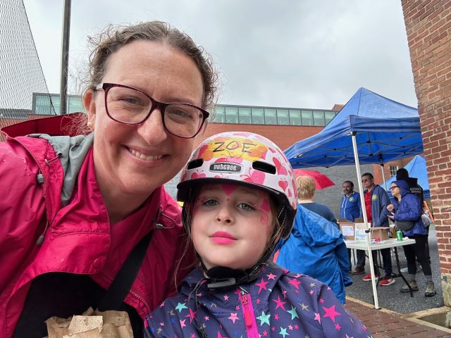 Councilmember Brianne K Nadeau takes a selfie with her daughter Zoe, posing in her bike helmet, at Bancroft Spring Fair.