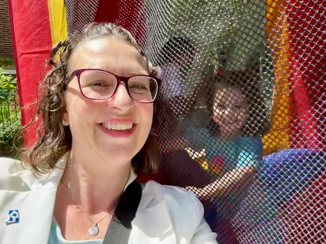 Councilmember Brianne K Nadeau takes a selfie with her daughter, who is inside a moon bounce at the block party