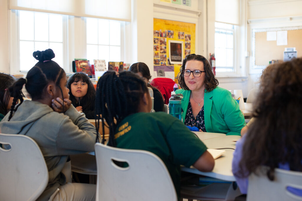 Councilmember Nadeau sits at a table and speaks with students.