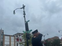 A firefighter stands in salute at the corner of 14th and Newton.