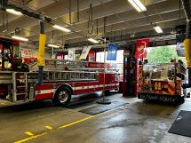 Inside the fire station, two fire trucks in view.