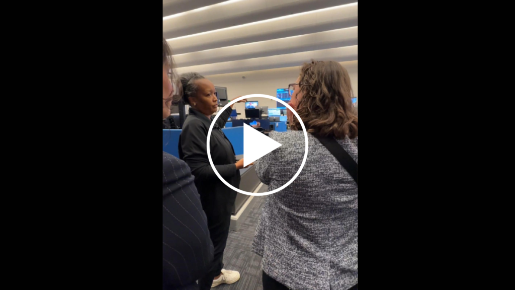 Screenshot of video showing three women looking at computer screens with white play button over the photo