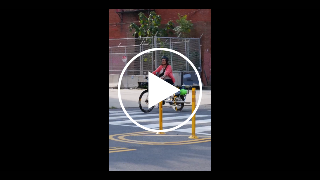 Screenshot from video of Councilmember Brianne Nadeau riding her bike wearing a helmet. Play button appears over the photo.