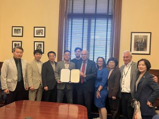 Councilmembers Nadeau and Frumin sit across a conference table from  members of the delegation from Incheon, South Korea. Chairman Mendelson is seated at one end of the table, his back to the camera, while a member of the South Korean team sits across from him.