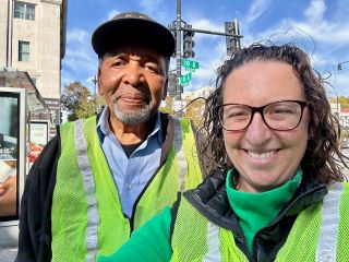 Selfie with Dr. Frank Smith and Councilmember Nadeau. Both are wearing yellow safety vests. A street sign is seen in the background.