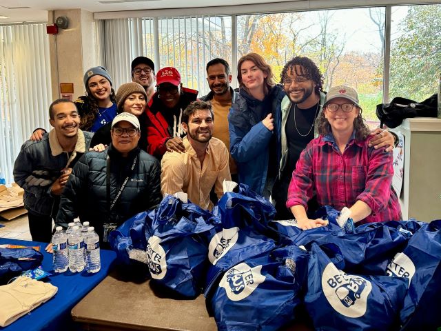 Councilmember Nadeau, staff, and volunteers - about ten altogether- pose in front of a table with turkeys in the lobby of a residential building.