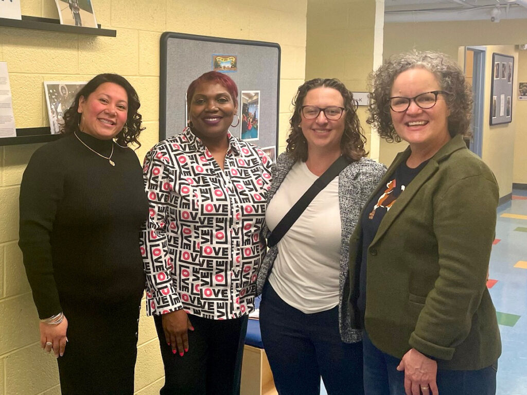 Councilmember Nadeau and three women pose for a photo in a hallway.