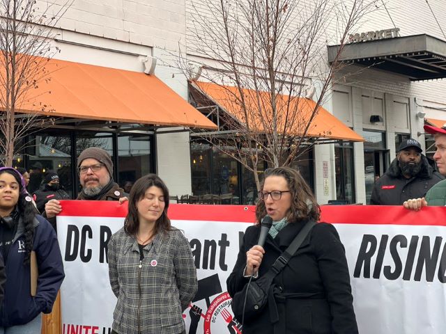 CM Brianne K Nadeau speaks into a microphone at a rally for restaurant workers.