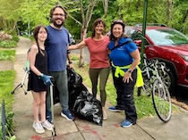 Councilmember Nadeau poses with a couple and their daughter with trash bags and trash picker.