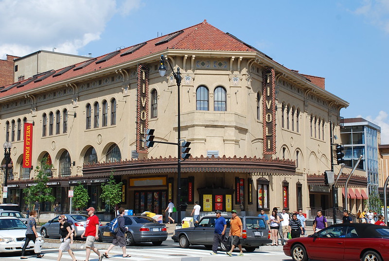A busy street with pedestrians, cars, and the Tivoli theater.