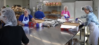 People wearing aprons and hairnets working in a kitchen environment