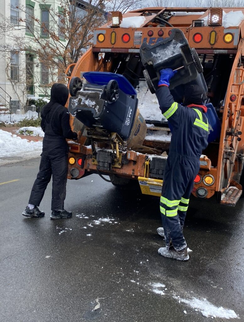 DC DPW workers dump trash bins into a truck