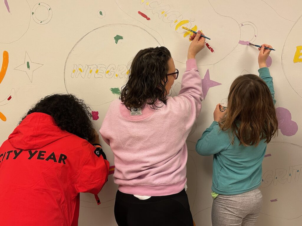 Three people paint a mural