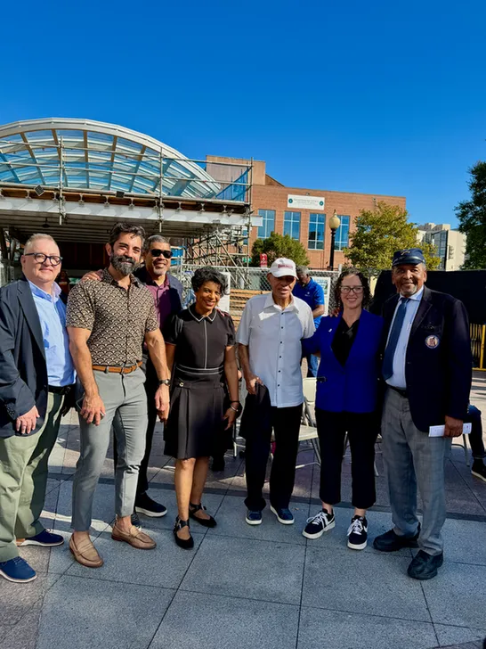 Seven people pose at the African American Civil War Museum and Memorial. The metro station is visible in the background.